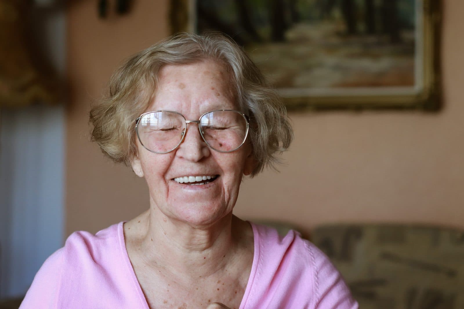 Señora mayor con gafas riendo en el salón de su casa — cuidado de mayores a domicilio en Canet de Mar